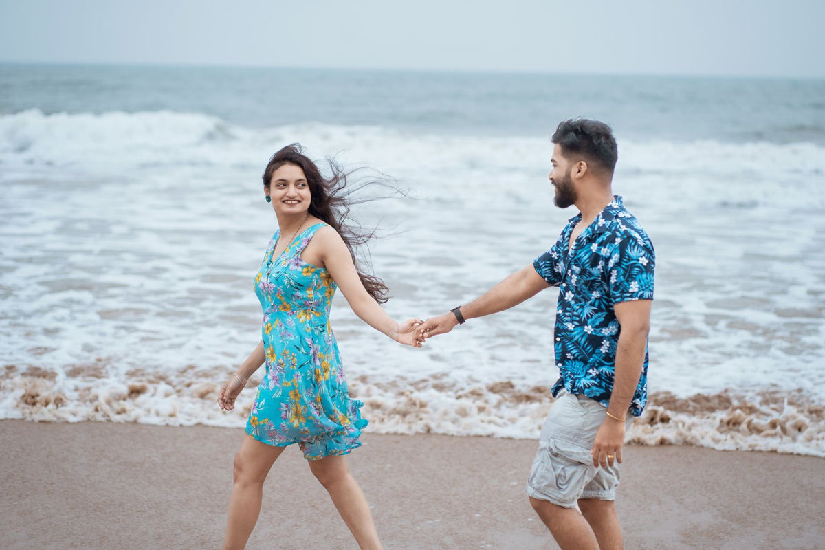 Lächelndes Paar geht Hand in Hand am Strand spazieren
