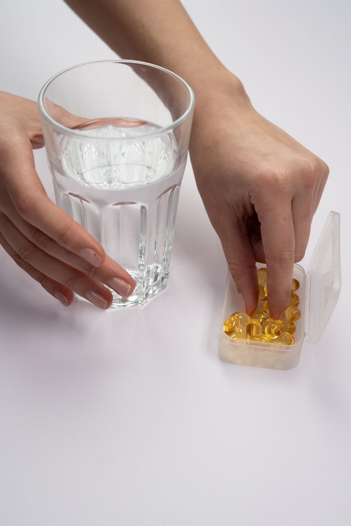 Softgel-Kapsel neben einem Glas Wasser