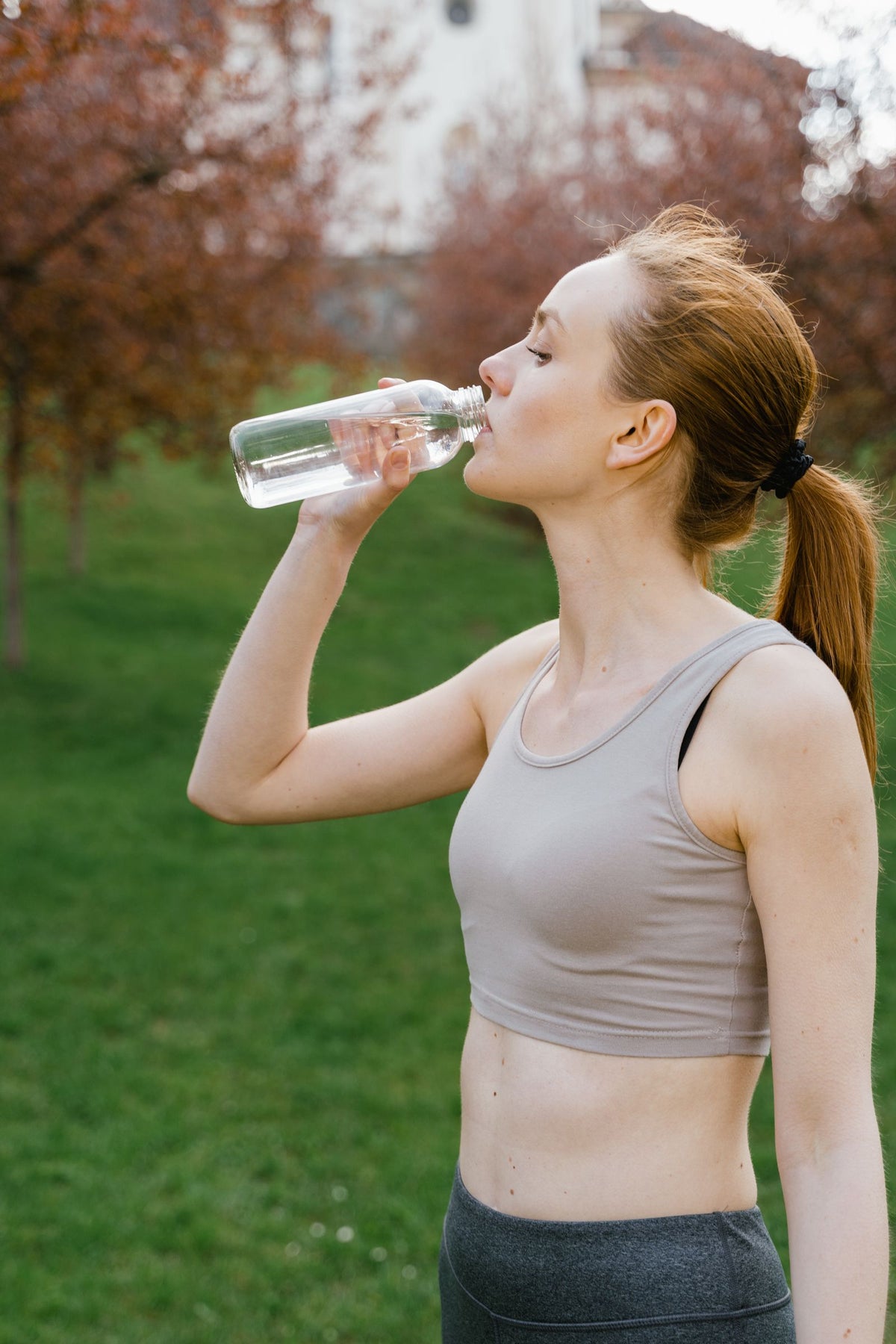 Frau in Sportkleidung trinkt aus einer Wasserflasche